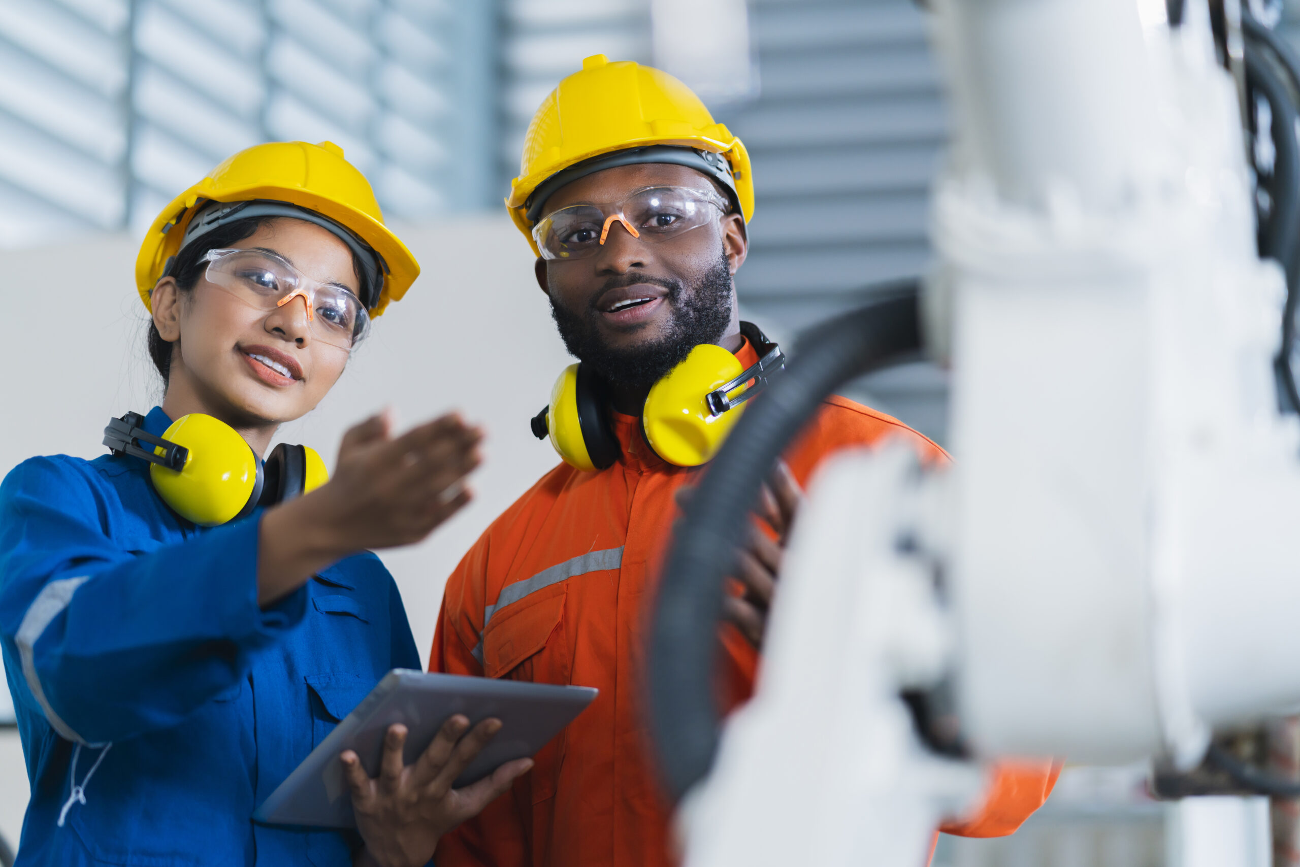 engineer cooperation male and female technician maintenance control relay robot arm system welding with tablet laptop to control quality operate process work heavy industry 4.0 manufacturing factory